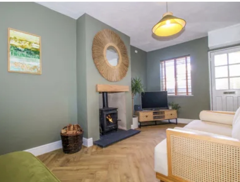 Sage green living room with wood-burning stove and warm timber floor