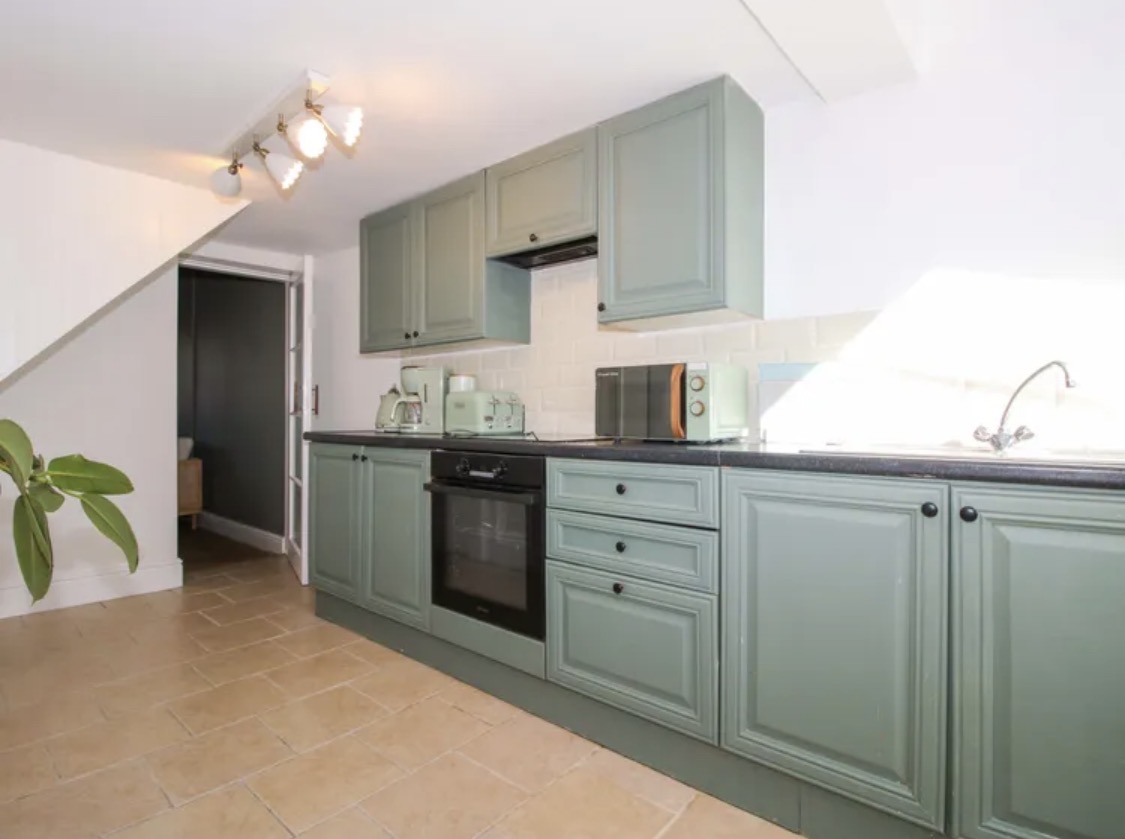 Kitchen with muted green cabinetry and light walls