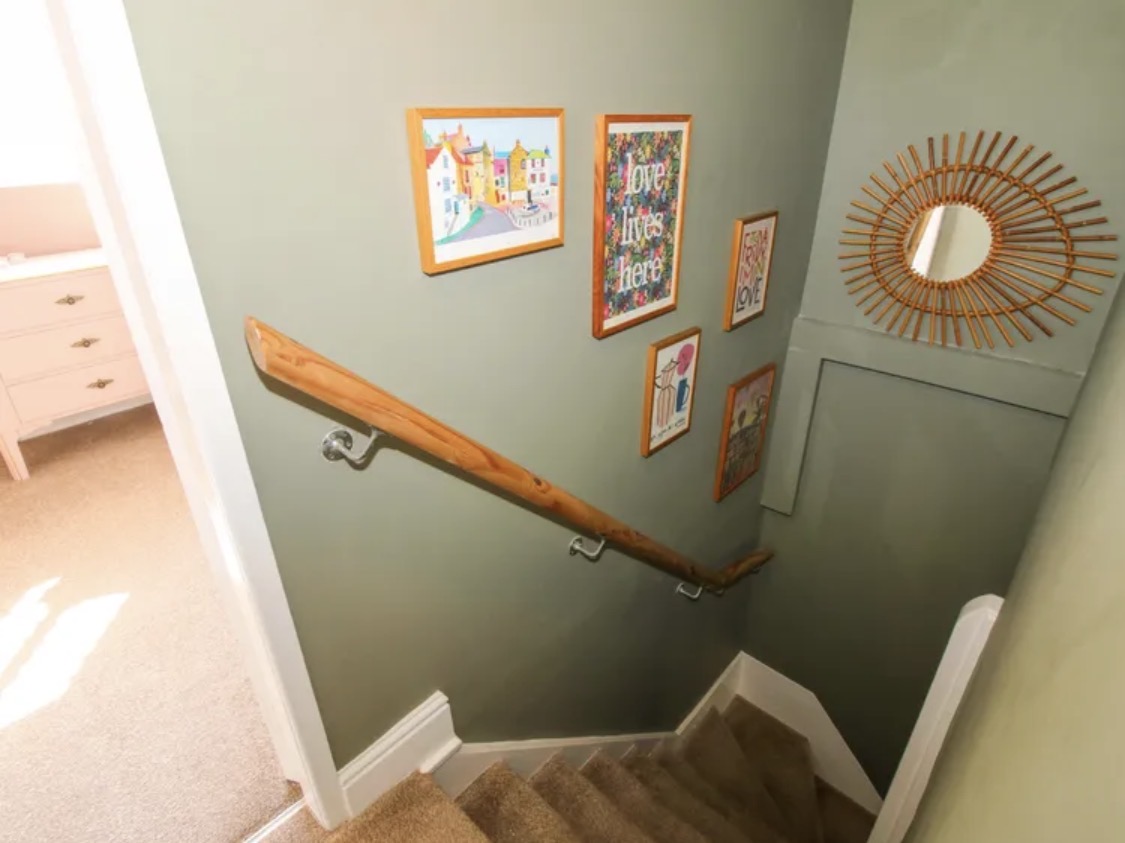 Sage green stairwell with white trim and timber handrail