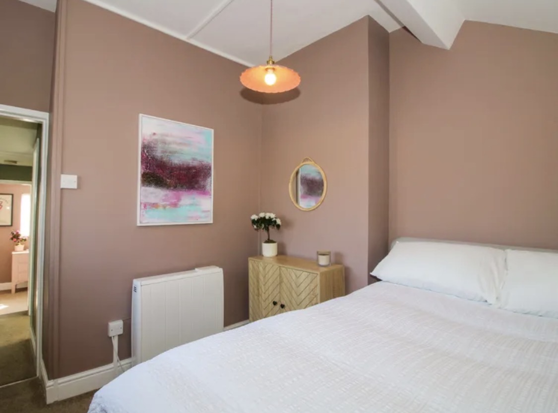Bedroom with warm pink walls and crisp white ceiling