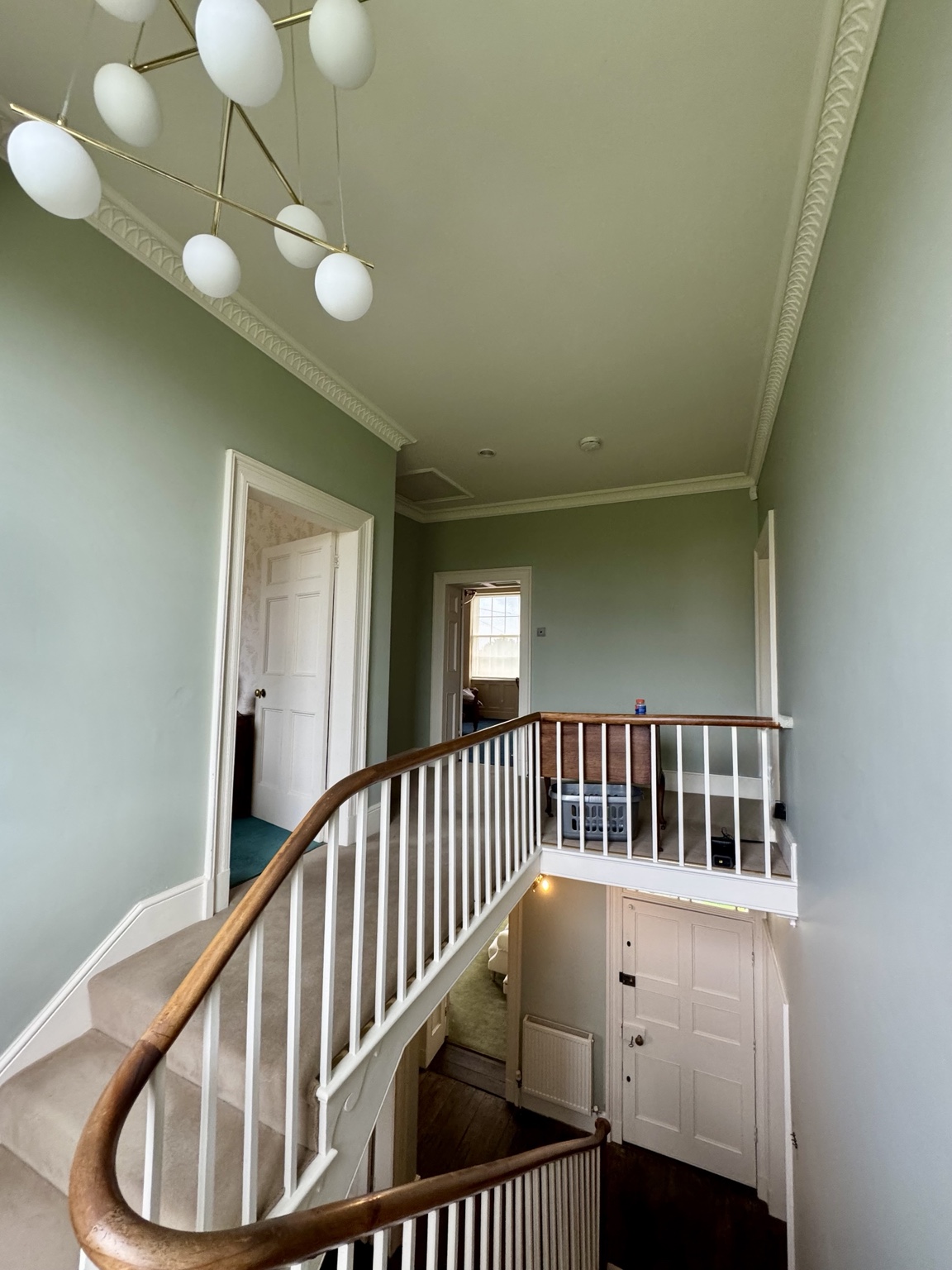 Upper landing after, with soft green walls and white trim